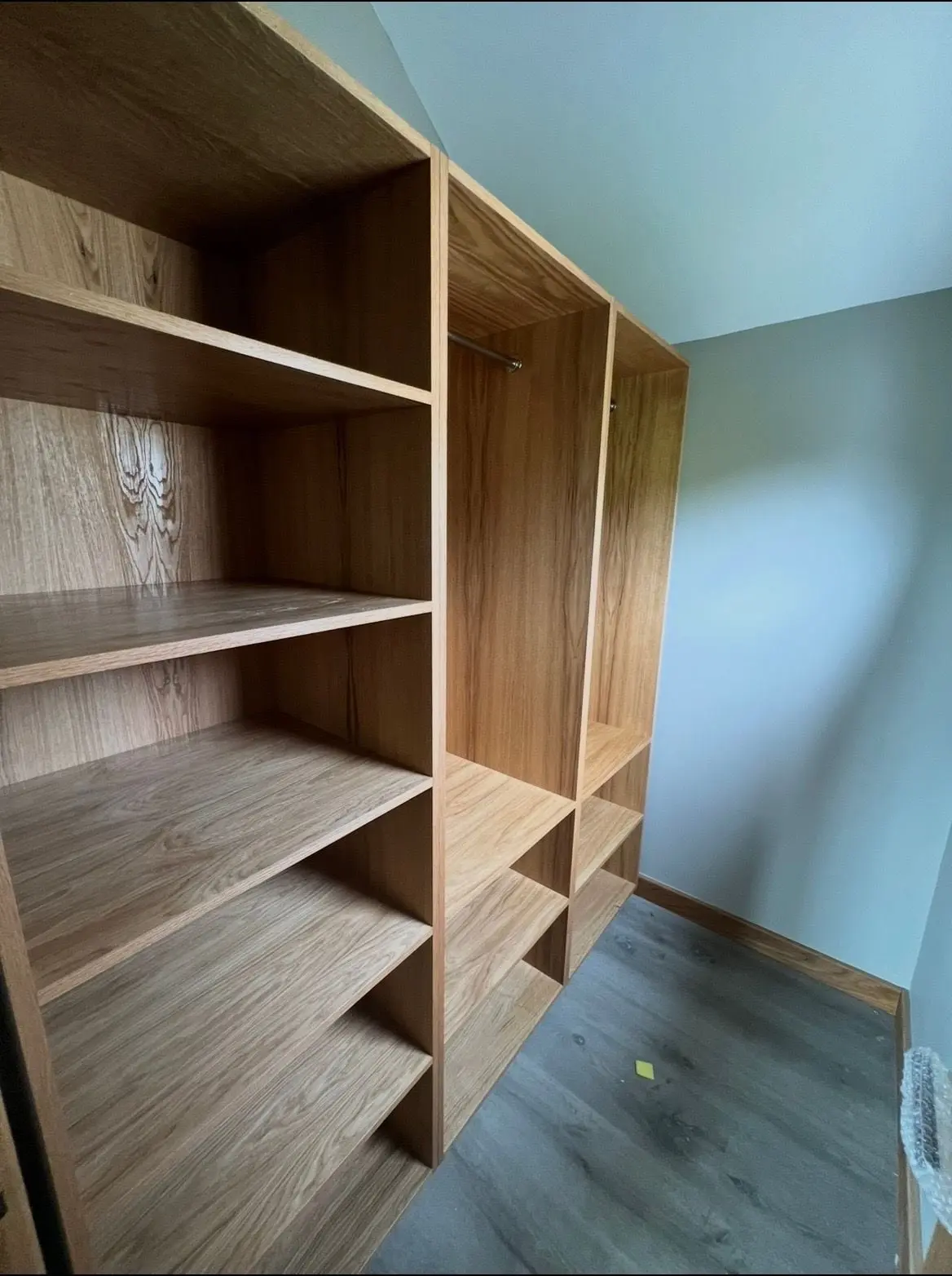 Fitted oak wardrobe with shelving and a hanging rail in a loft bedroom