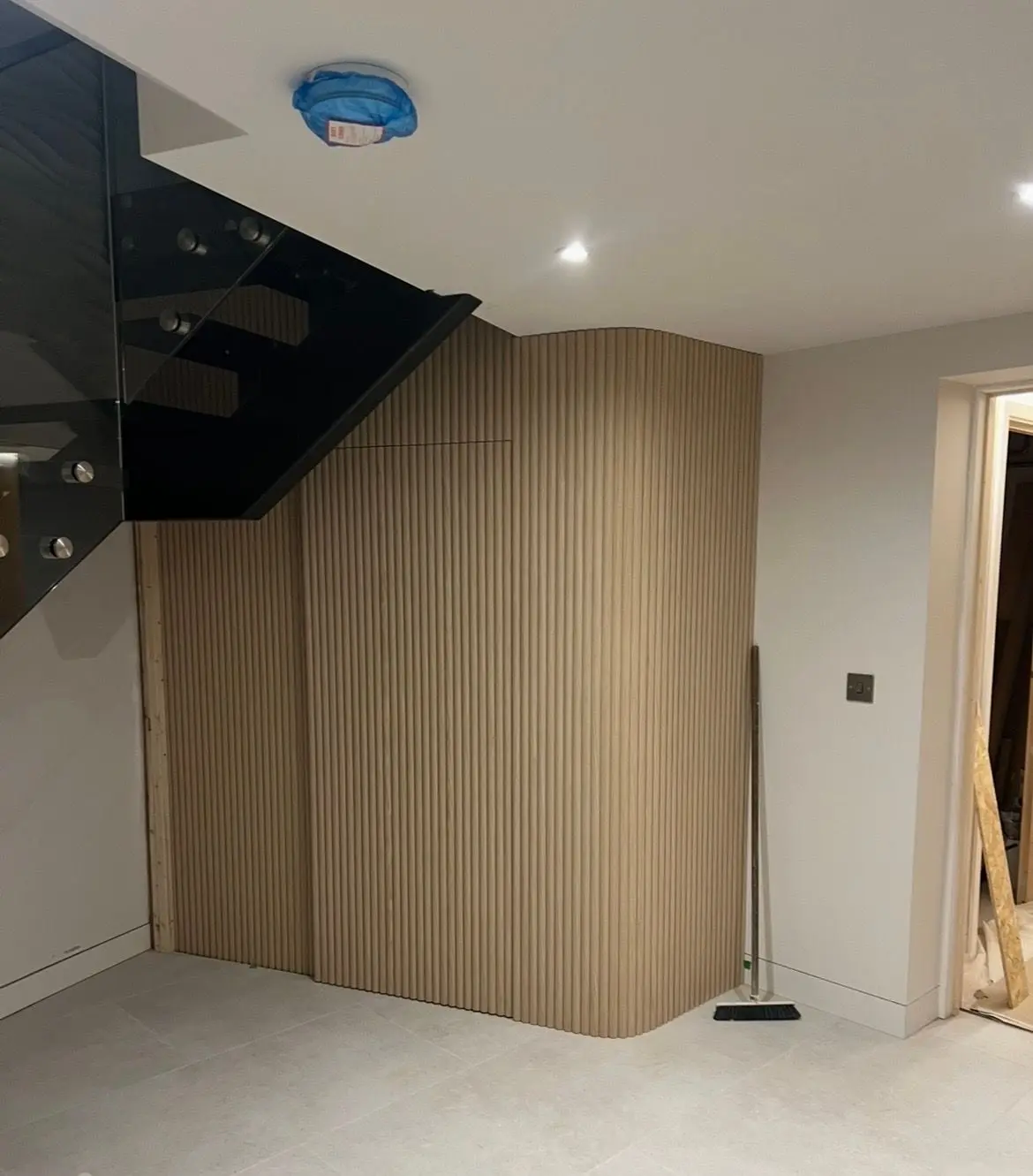 Fluted timber panelling on a curved wall beneath a floating staircase