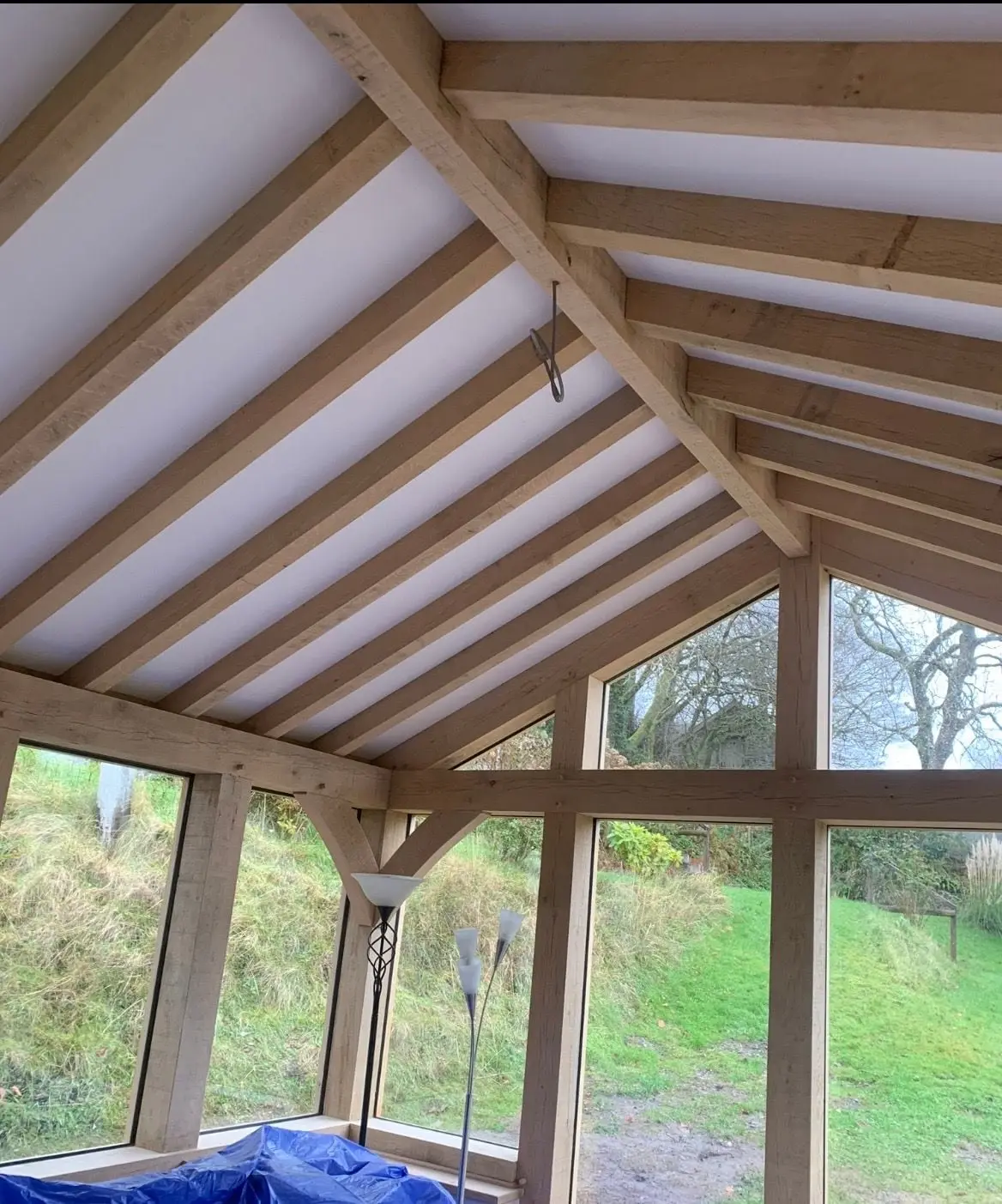 Exposed oak rafters and full height glazing looking out to a garden