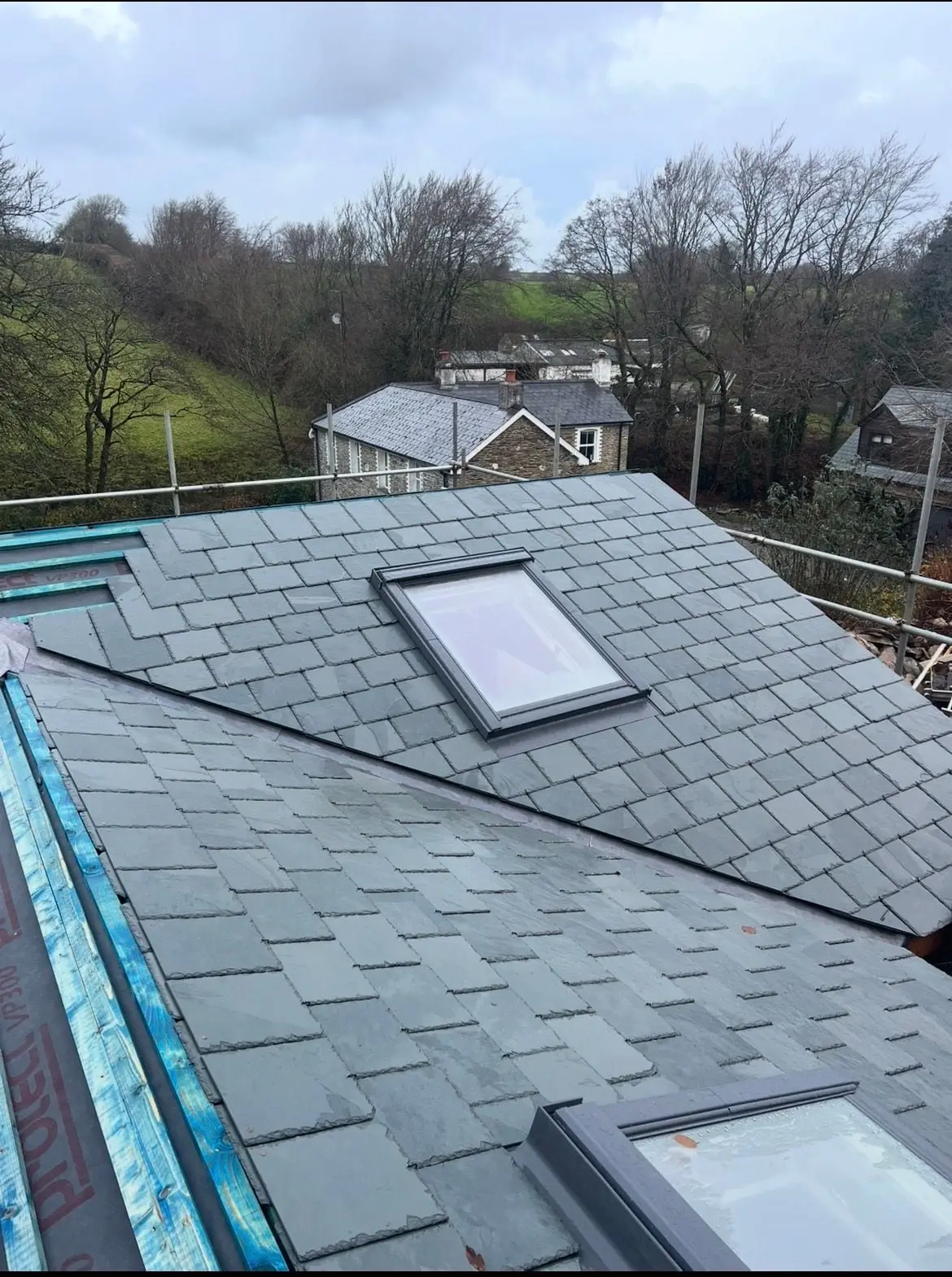 Slate roof seen from above, fields and trees beyond